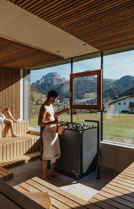 Zwei Personen entspannen sich in der Panoramasauna mit Blick auf die Berge
