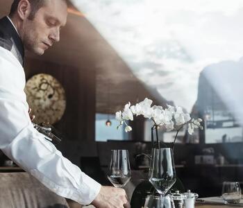 Kellner Angelo deckt einen Tisch mit Blick auf die Berge