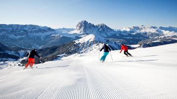 Three people are skiing in the sciing area Dolomiti Superski