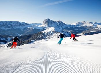 Tre persone che fanno una sciata nel comprensorio sciistico Dolomiti Superski