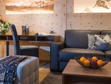 Details der Einrichtung im Wohnbereich: der Schreibtisch, die Couch, ein Fußhocker und ein Beistelltisch