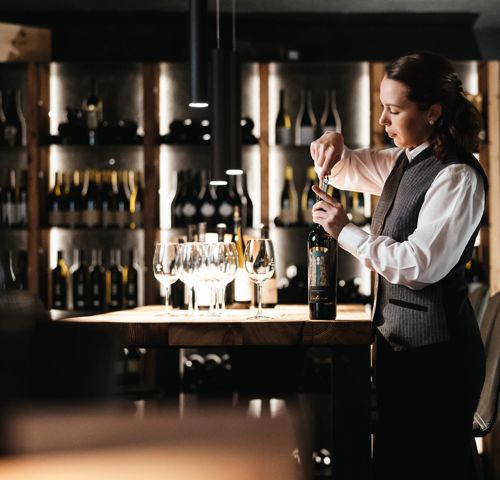 Eine Frau öffnet eine Flasche Wein