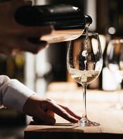 A man is pouring a glass of white wine