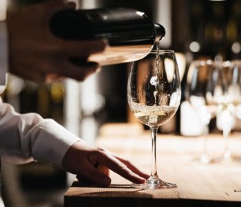 Ein Mann schenkt ein Glas Weißwein ein