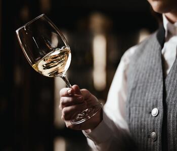 A woman is holding a glass of white wine