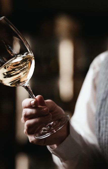 Eine Frau hält ein Glas Weißwein in der Hand