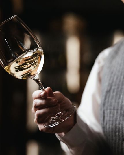 A sommelier swirls a glass of white wine.