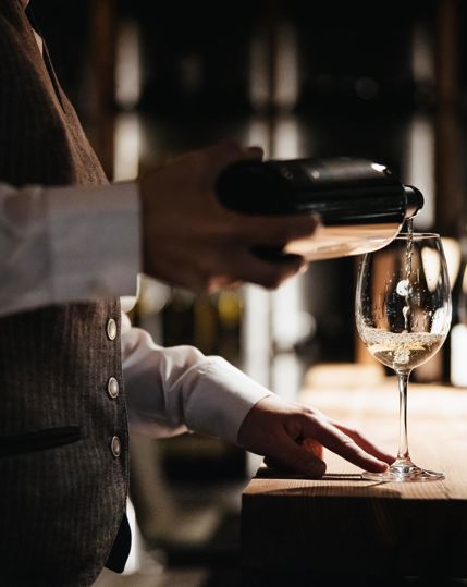A sommeliere is pouring a glass of white wine