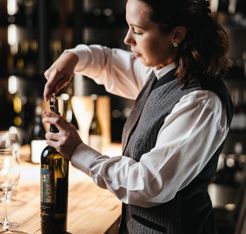 Eine Frau öffnet eine Flasche Wein