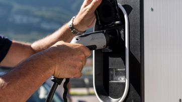 Un uomo ricarica la sua auto elettrica