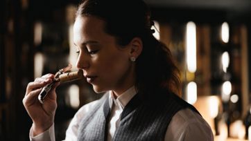 A sommeliere is sniffing the cork of a wine bottle